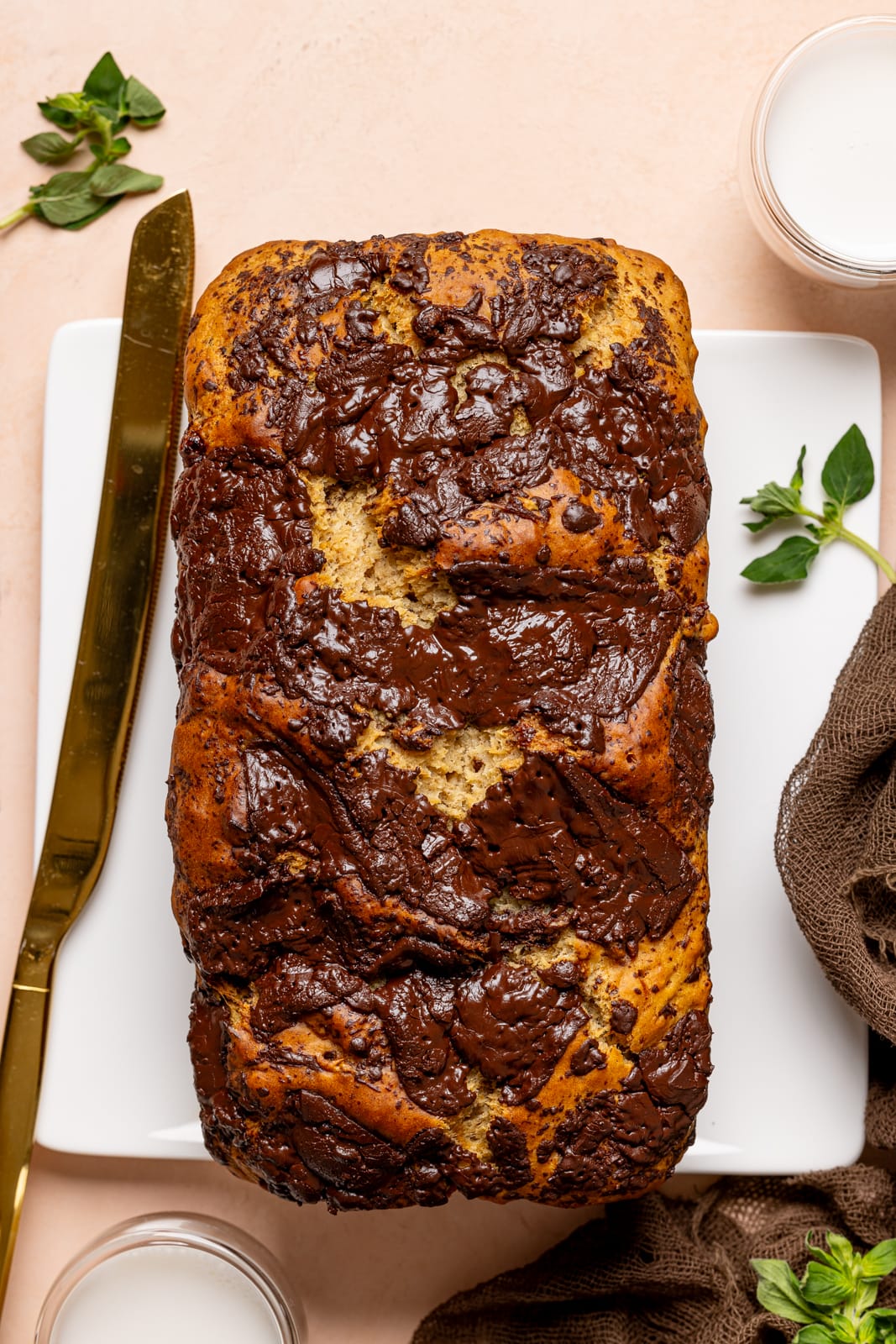 Baked bread on a white plate with a gold knife and glasses of milk.