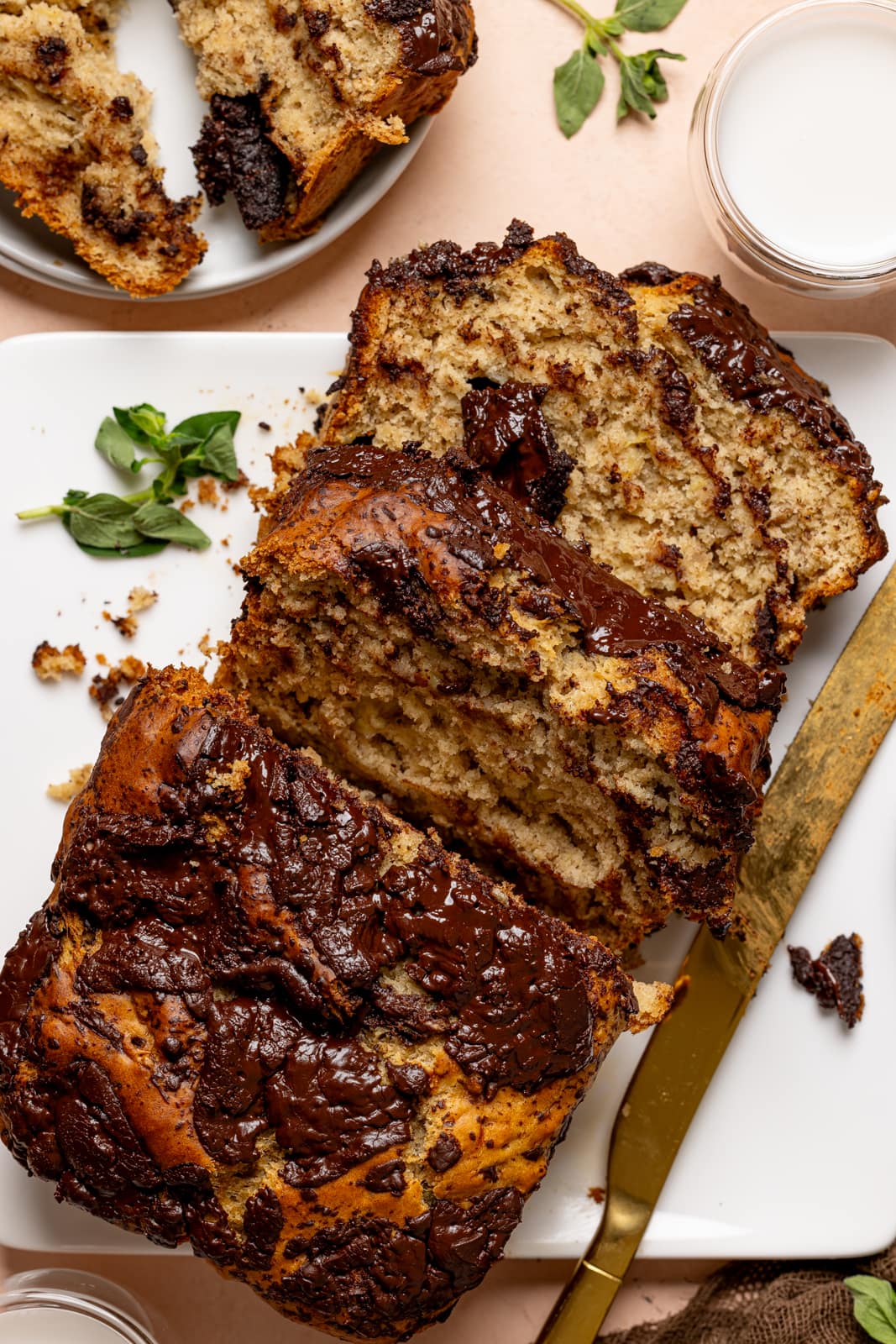 Baked bread with slices on a white plate with a knife and milk.