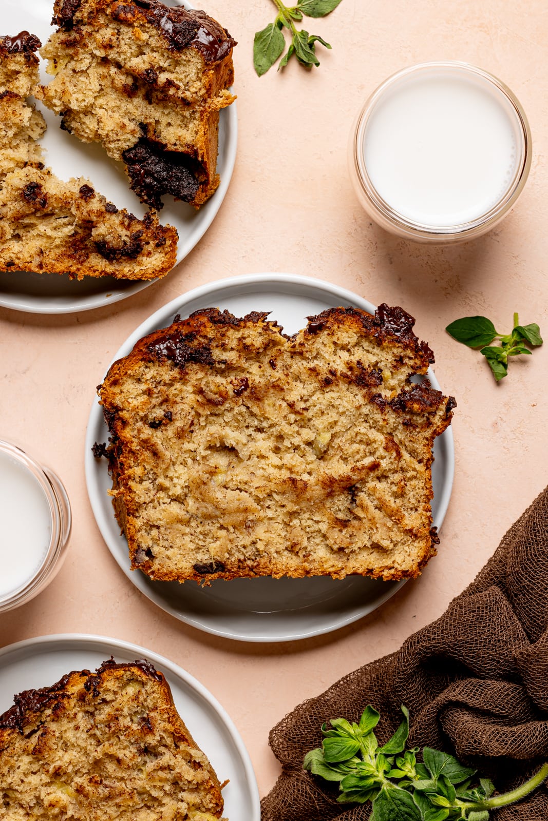 Bread sliced on three plates with glasses of milk.