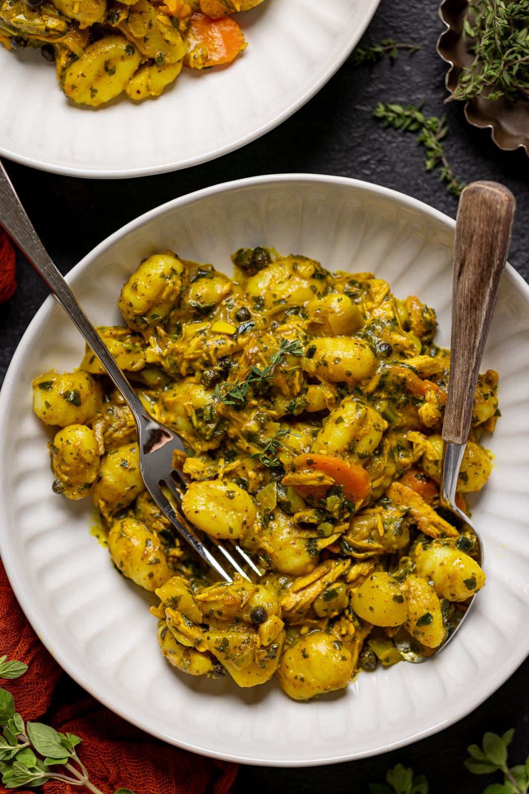 Chicken and gnocchi in a plate with a spoon and fork.