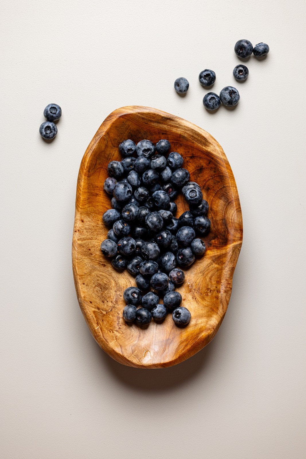 Blueberries in a brown bowl on a grey table.