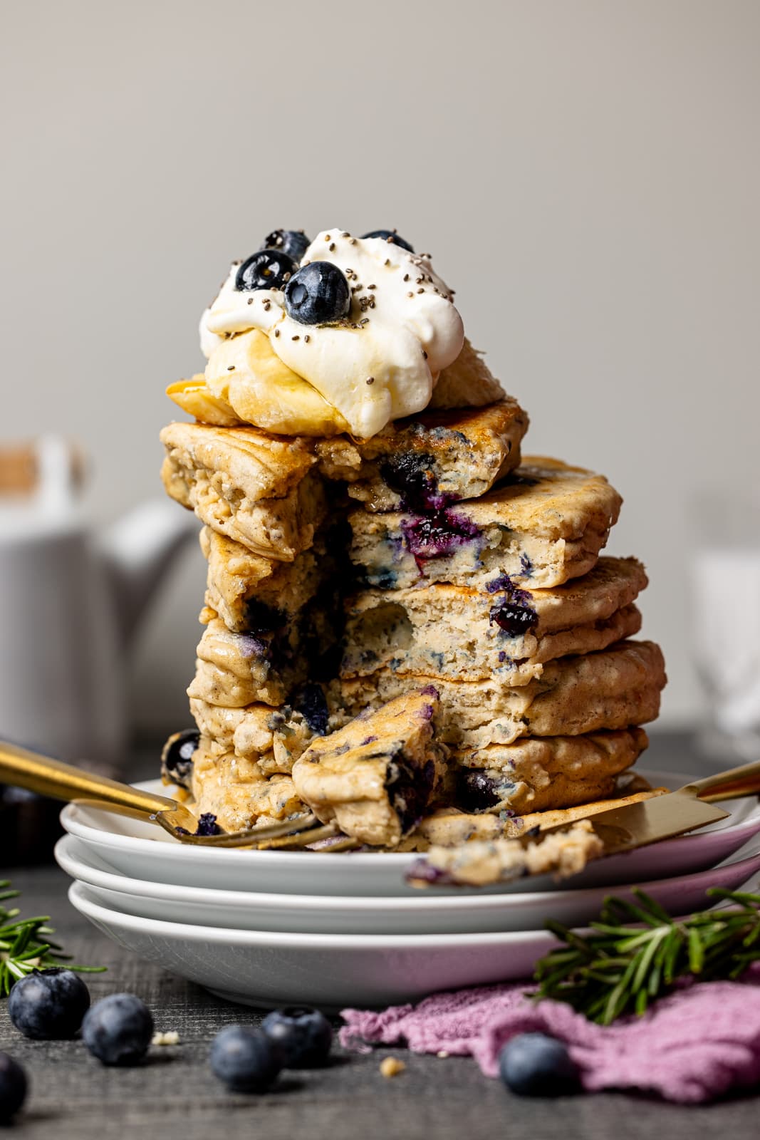 Stack of pancakes sliced with whipped cream and blueberries.