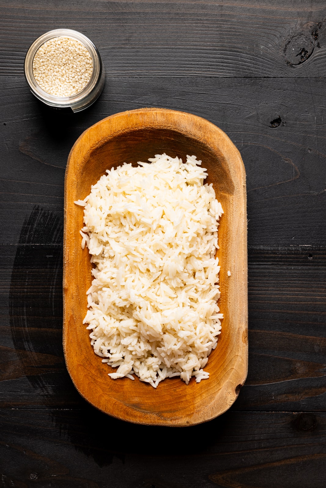 Cooked basmati rice in a brown bowl with sesame seeds. Ready for the healthy chicken recipe to be layered on top.