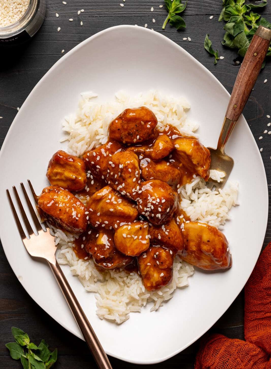 Chicken and rice in a plate with two forks on a black table.