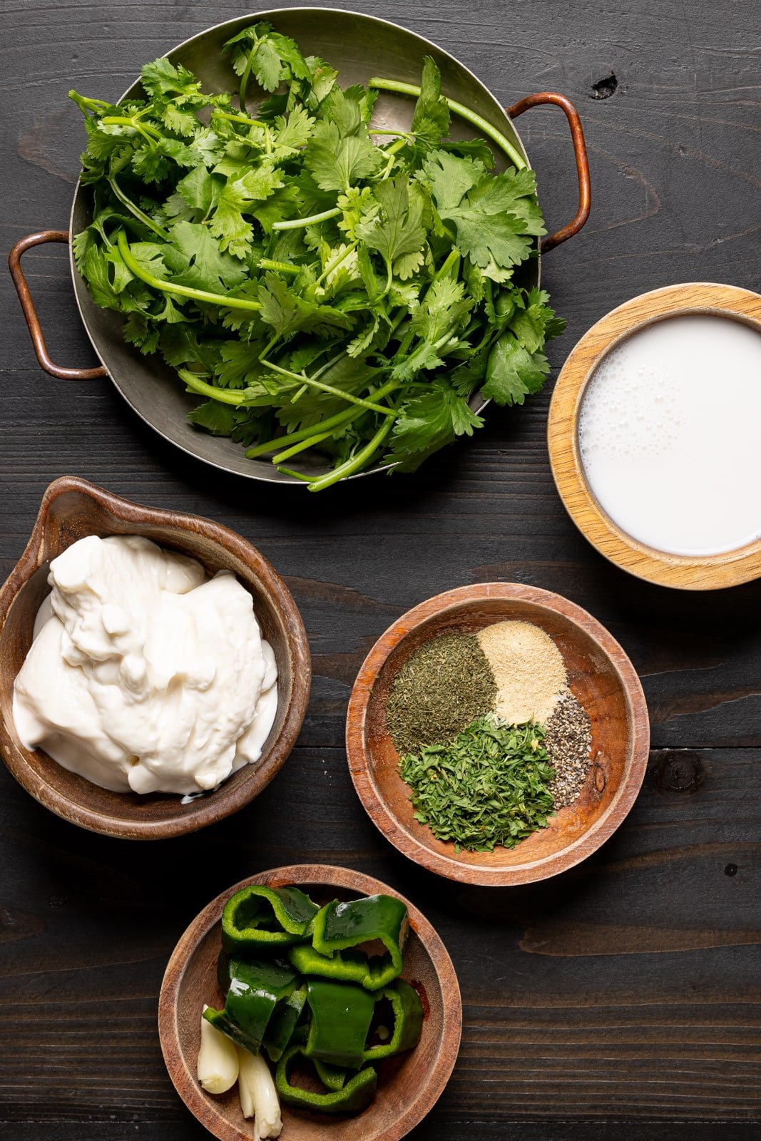 Green goddess dressing ingredients including cilantro, mayo, herbs + seasonings, peppers, and milk. 