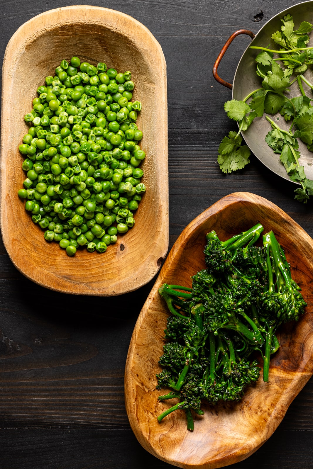 Green veggies on a black wood table.