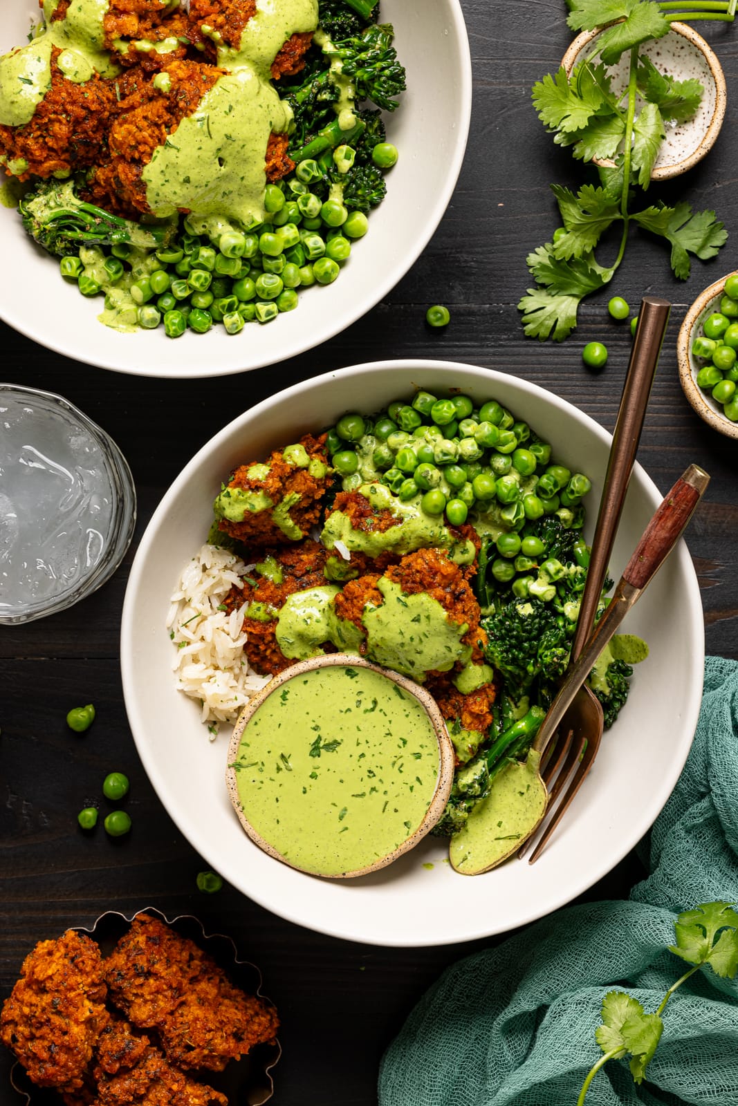 Two bowls of chicken with veggies and a glass of juice with herbs as garnish.