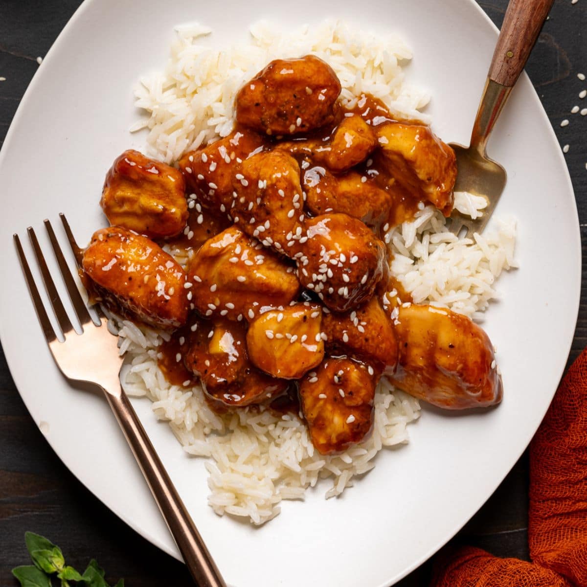 Chicken and rice in a plate with two forks on a black table.