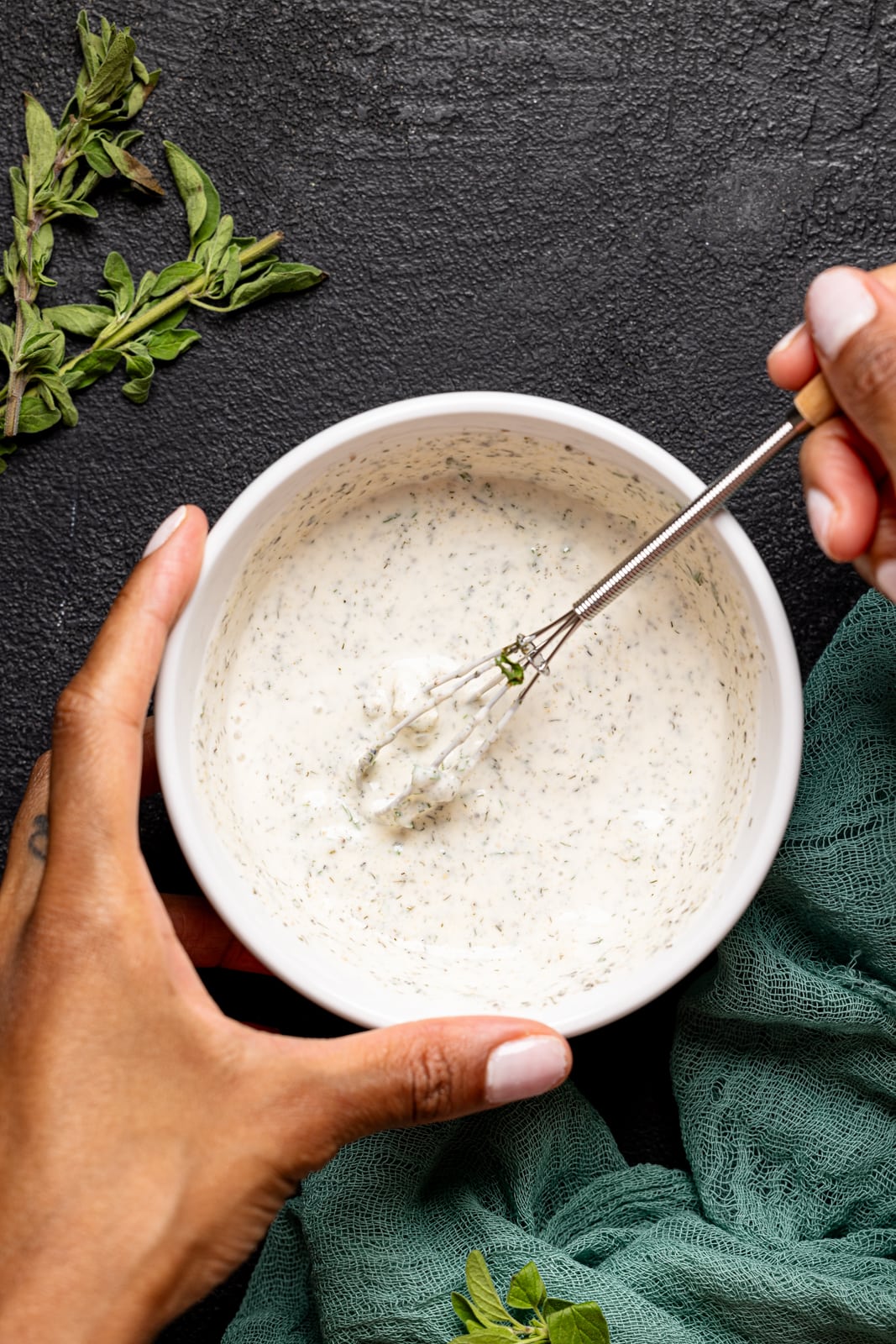 Dressing in a white bowl being held with a whisk.