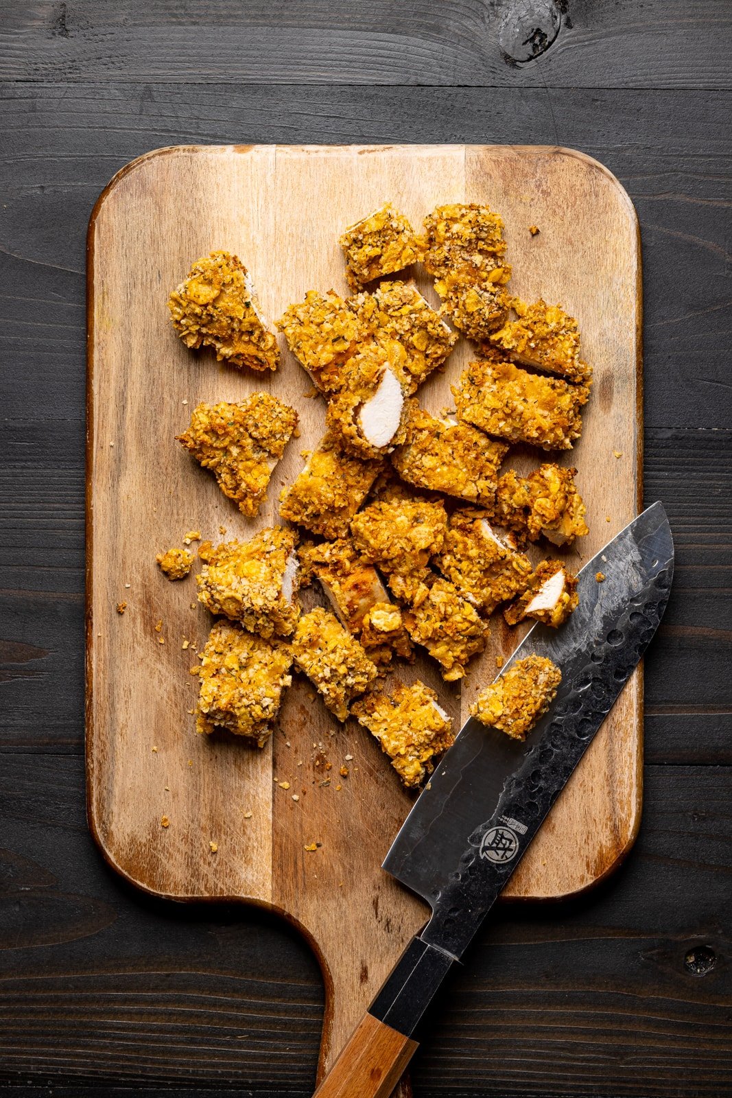 Chopped crispy chicken on a cutting board with a knife. 