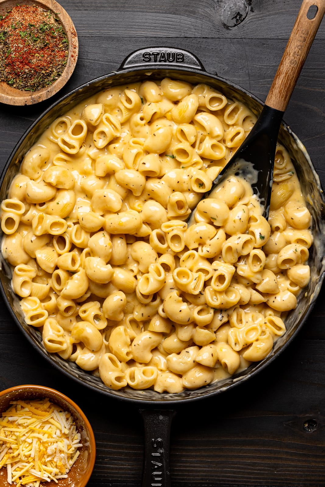 Cooked cheesy mac and cheese in a black skillet with a spoon.