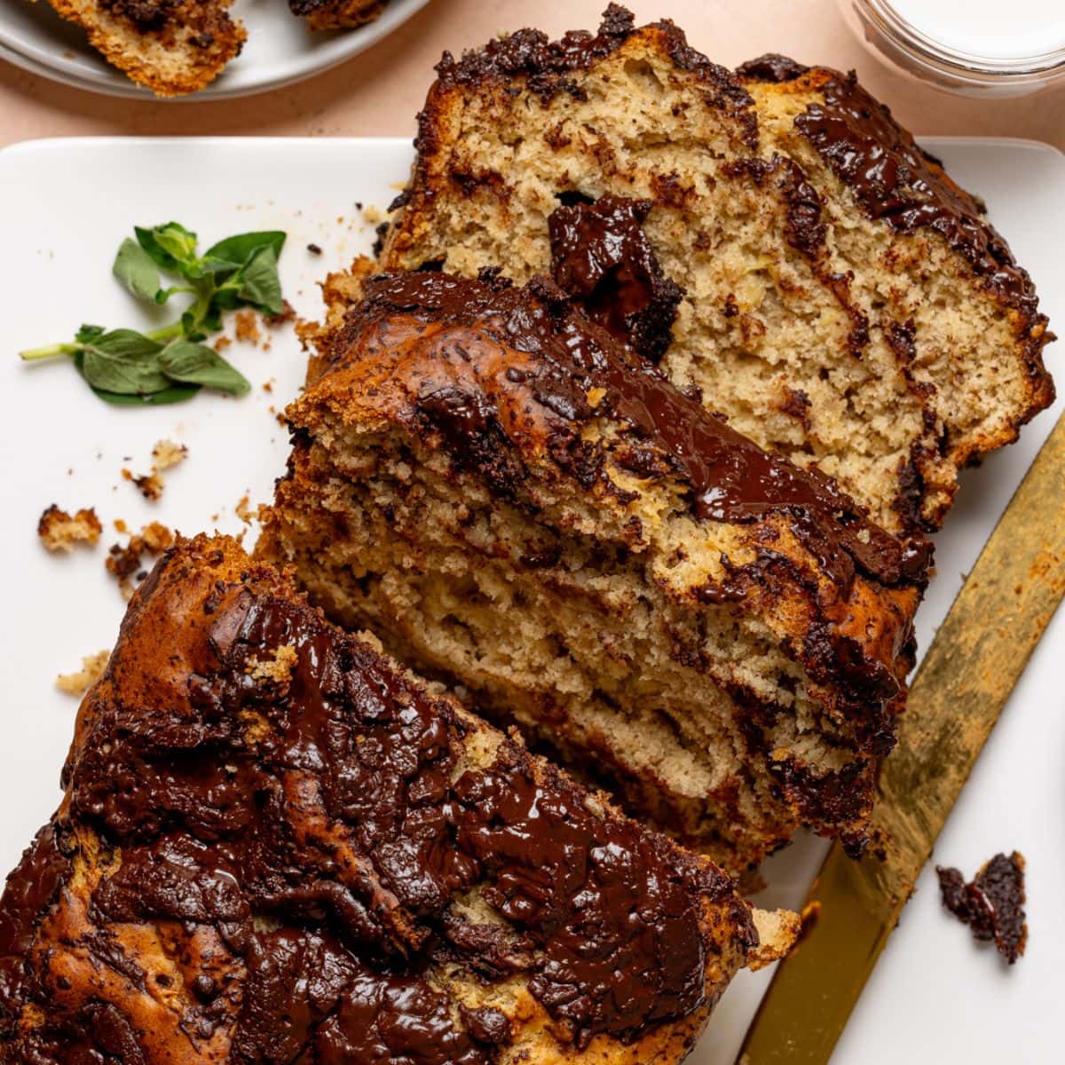 Baked bread with slices on a white plate with a knife and milk.