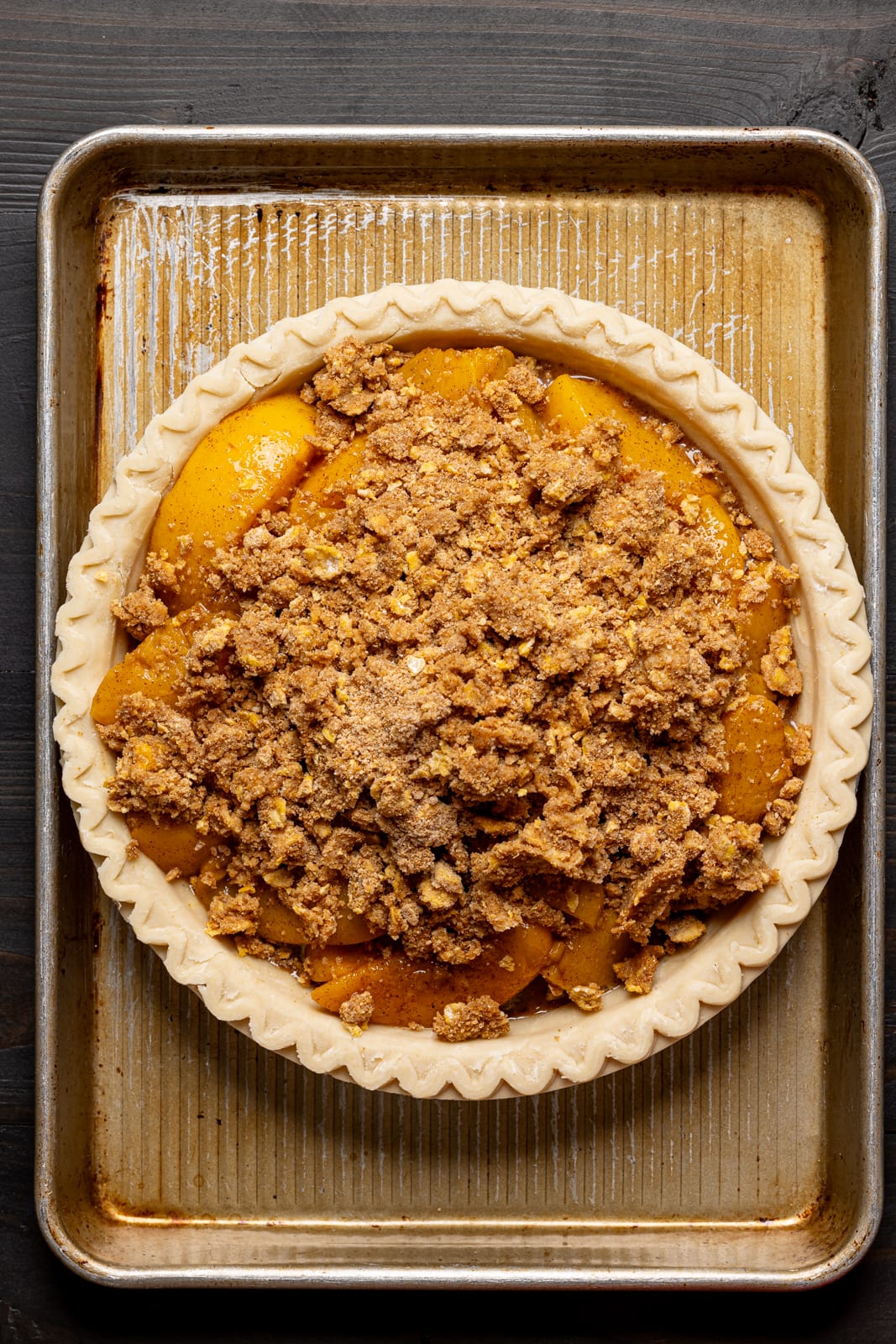Peach filling and topping in a crust on a baking sheet. 