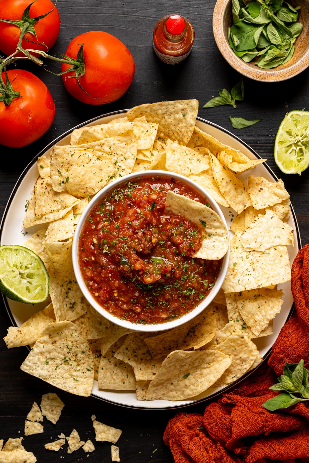 Dip and chips with tomatoes, lime, and garnish.