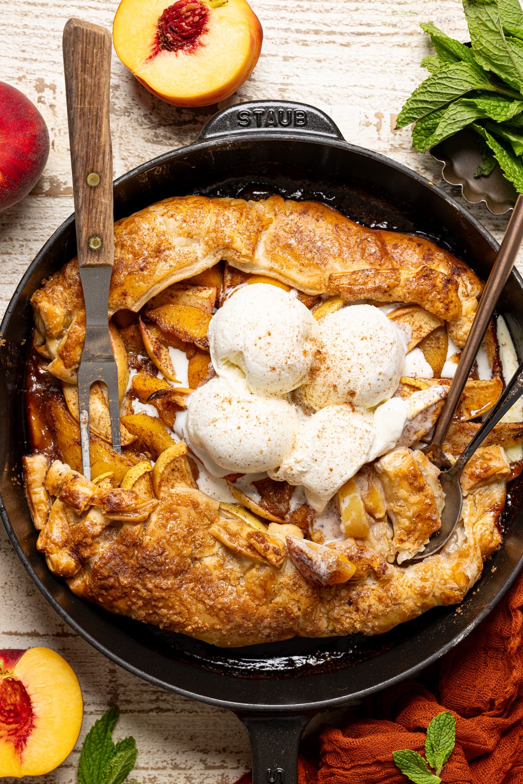 A skillet with scoops of ice cream, a fork, and two spoons. 