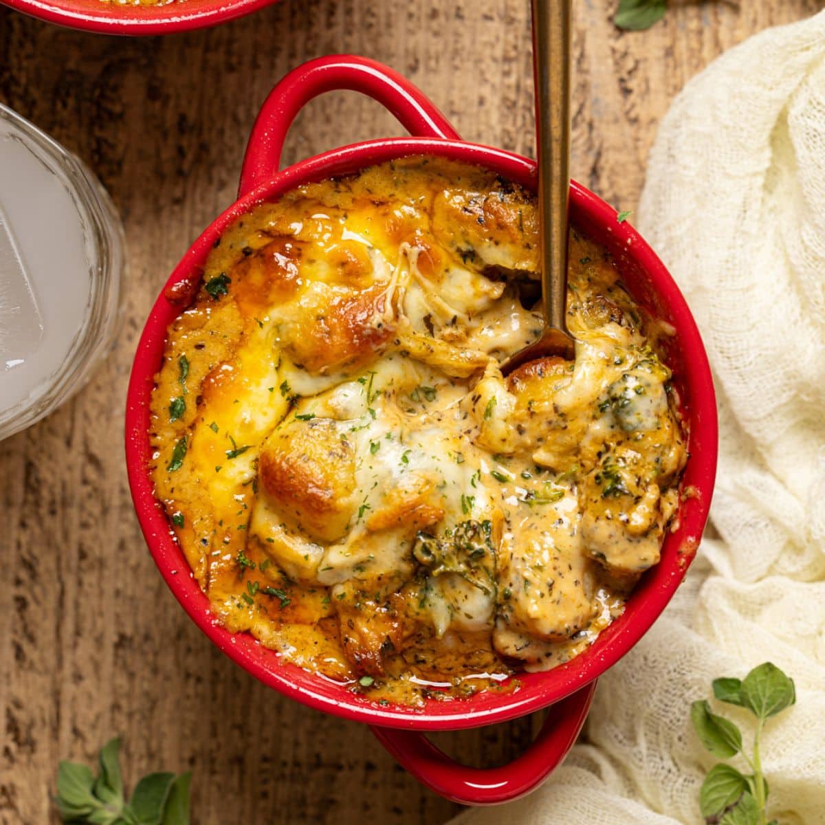 Up close shot of baked gnocchi with a spoon and drink.