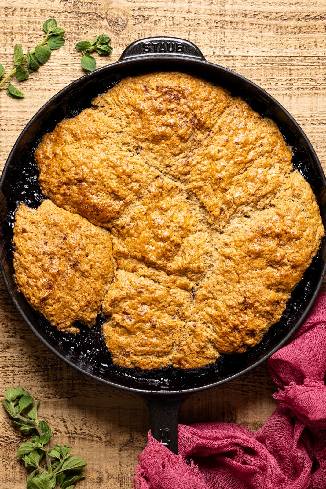 Baked cobbler in a black skillet on a brown wood table.