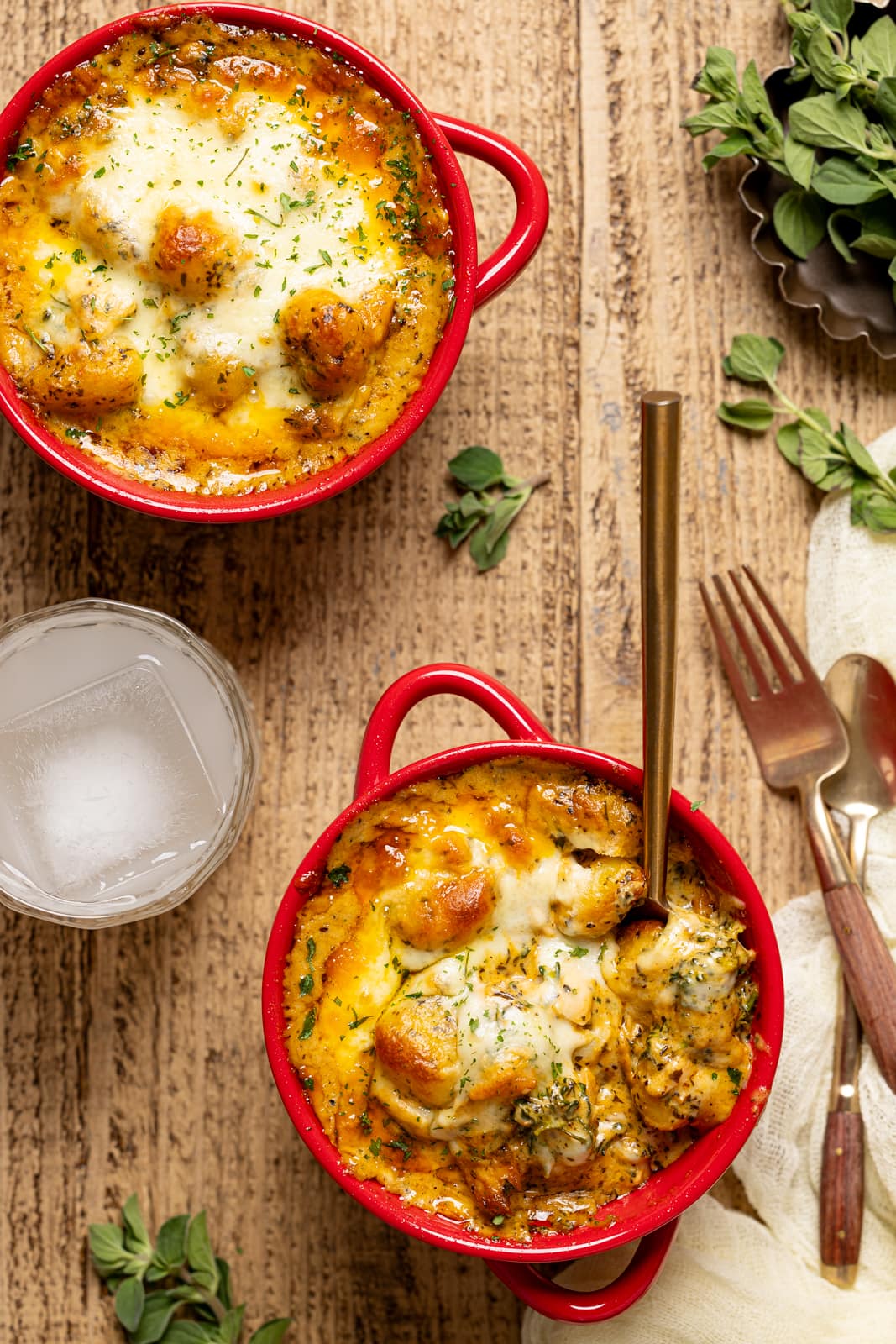 Up close shot of baked gnocchi in red bowls with fork and spoon.