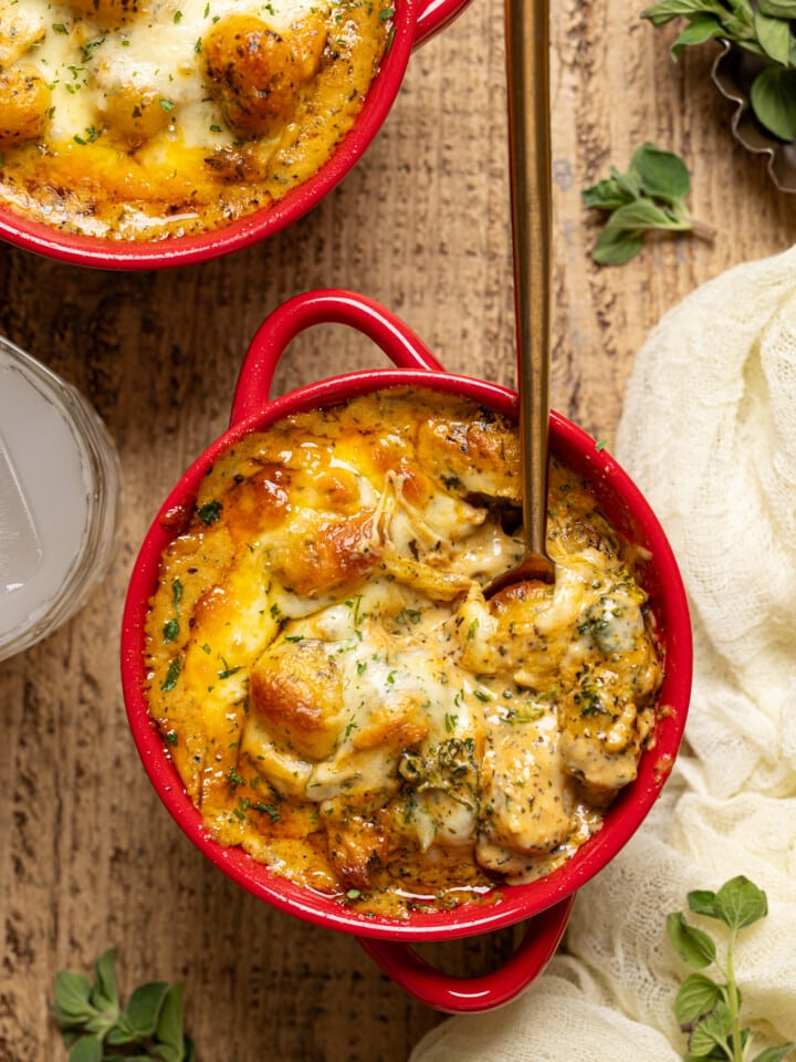 Up close shot of baked gnocchi with a spoon and drink.