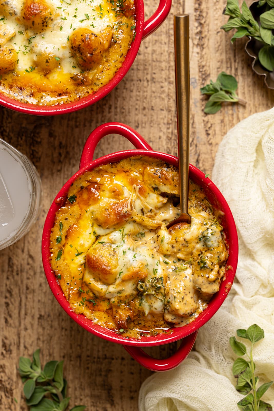 Up close shot of baked gnocchi with a spoon and drink.