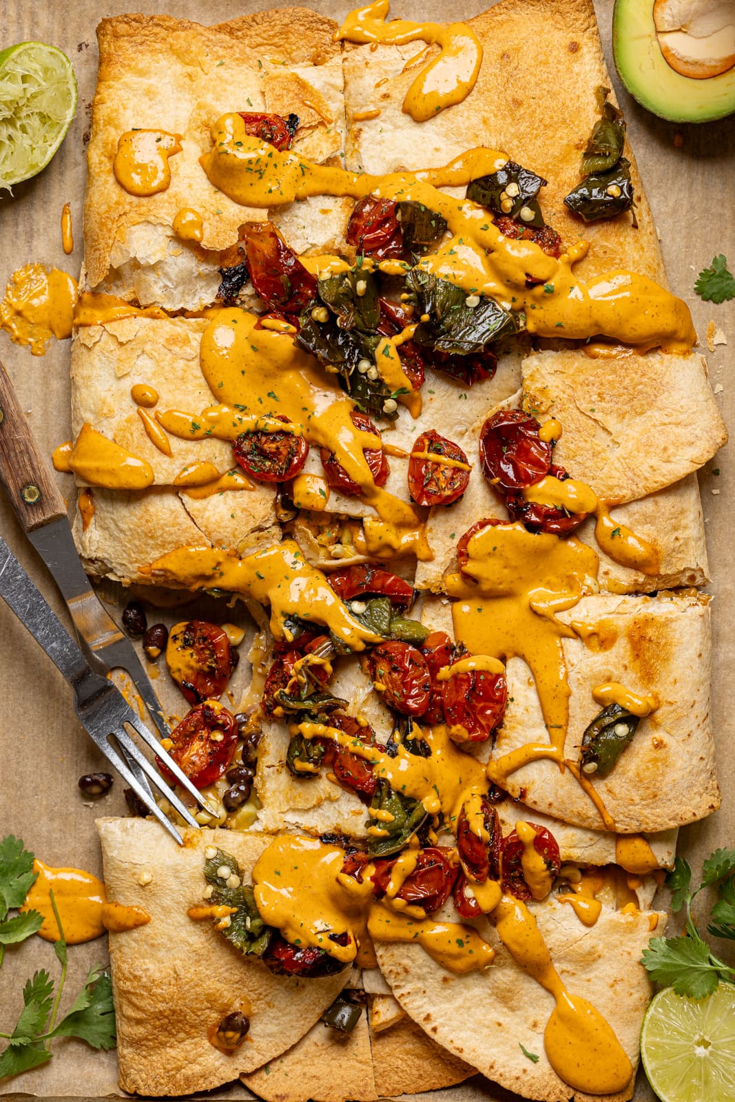 Quesadilla chopped on a baking sheet with toppings and two forks. 