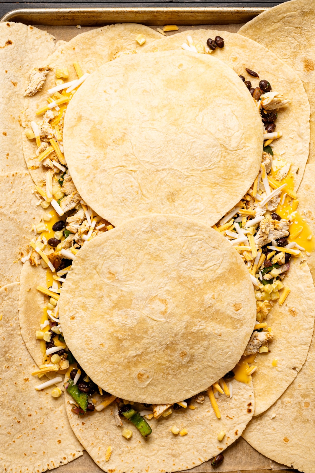 Sautéed beans, chicken, and shredded cheese spooned atop tortillas and then topped with two tortillas. 