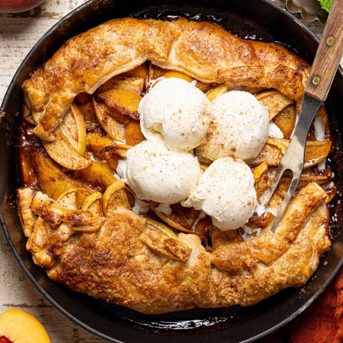 Galette in a black skillet with a fork and scoops of ice cream.