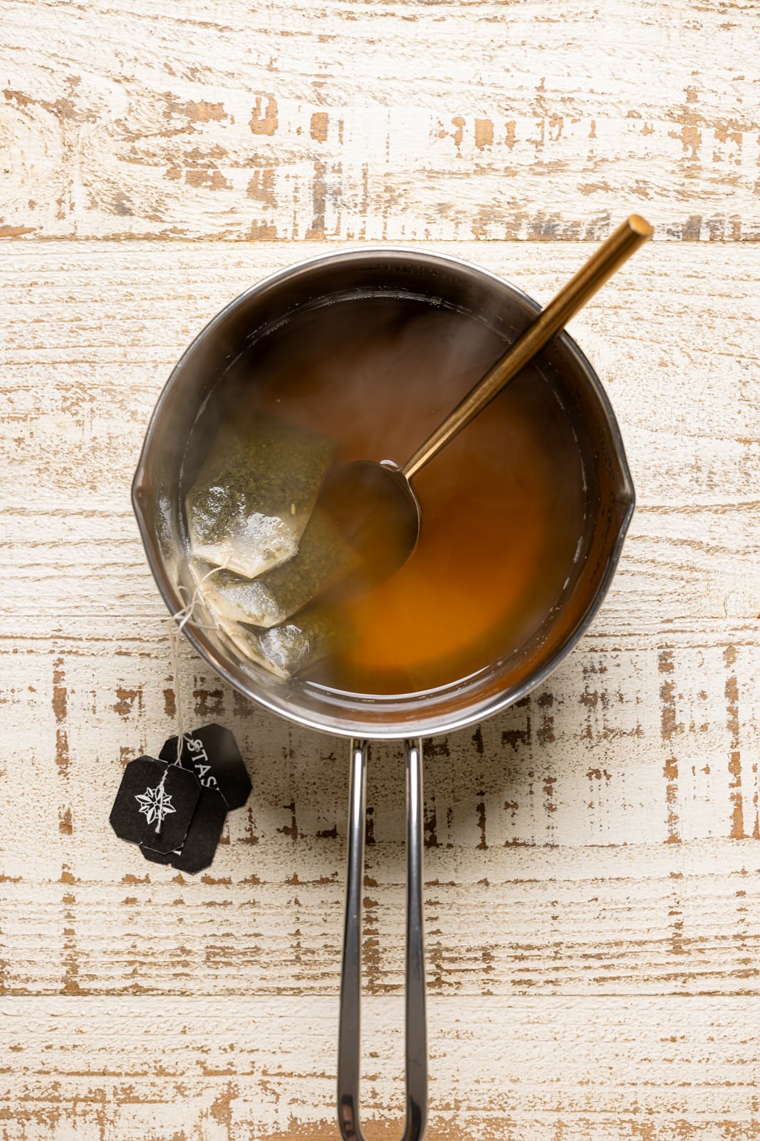 Green Tea mixture in a silver saucepan with tea bags.