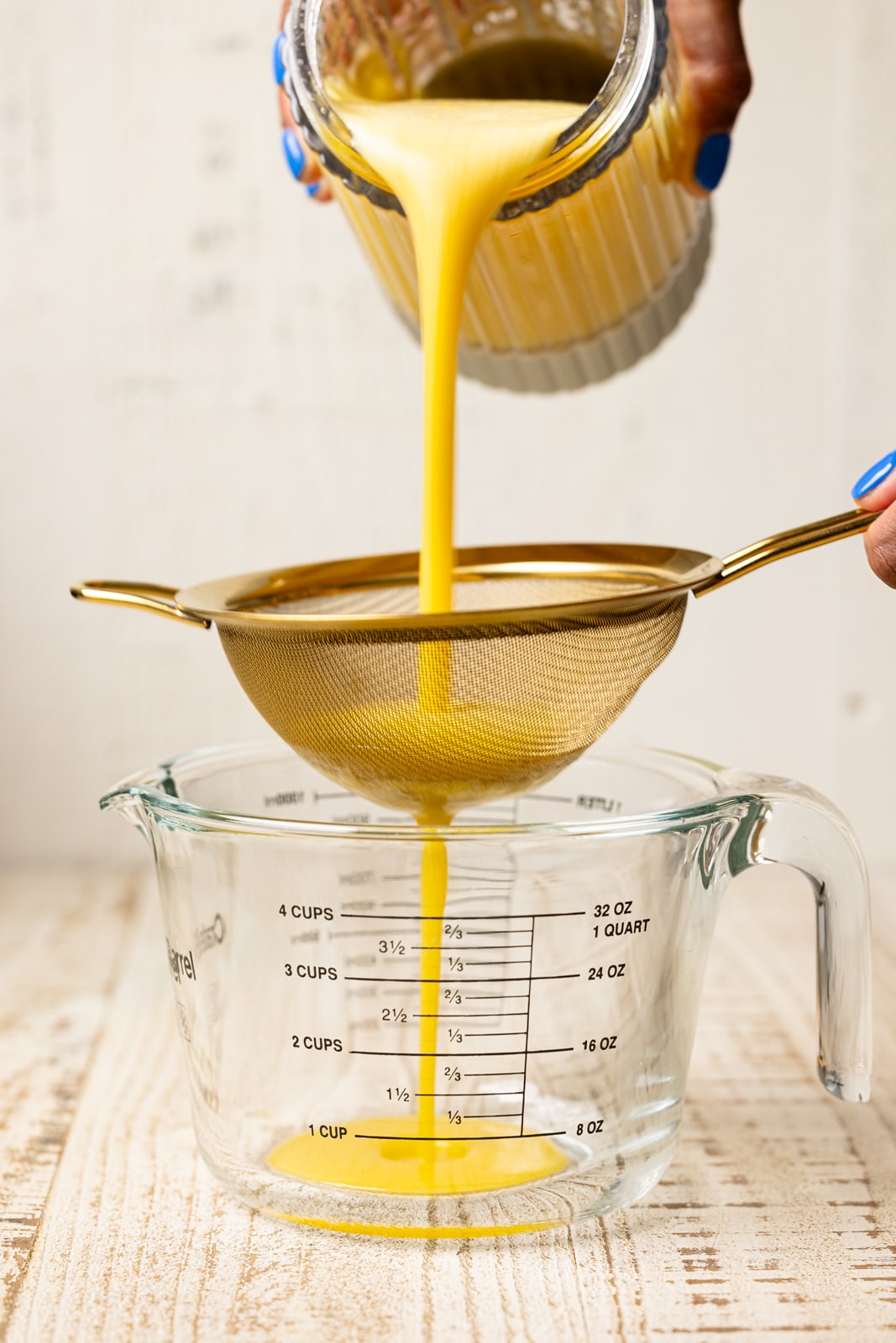 Pouring juice through a strainer in a measuring cup.