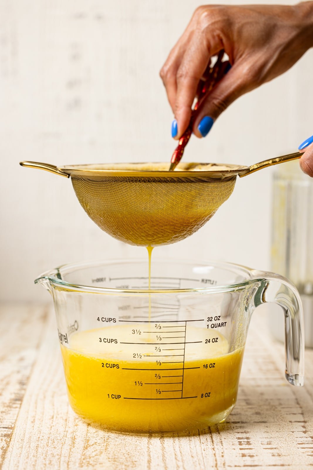 Straining juice mixture into a measuring cup.