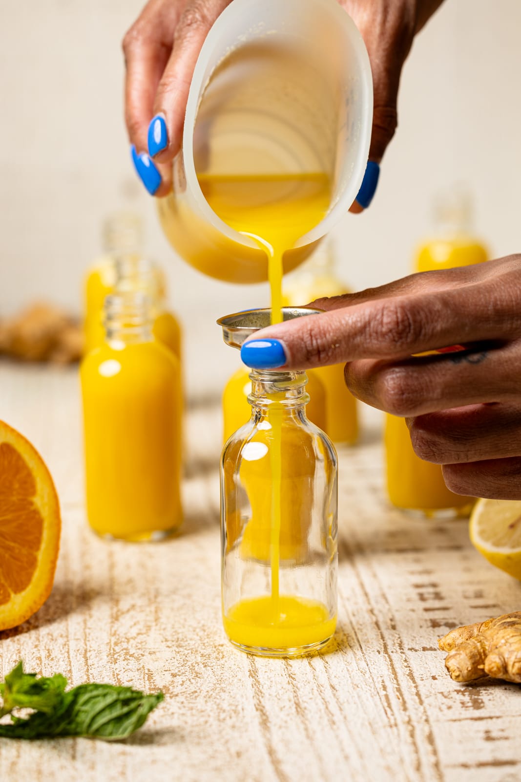 Pouring green tea shot recipe into a mini bottle.