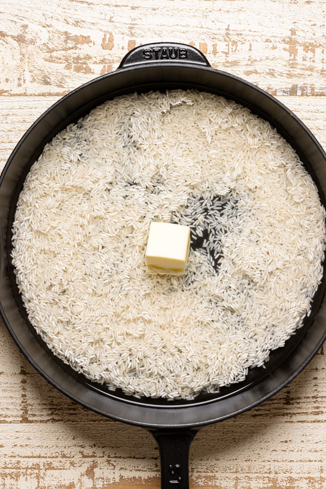 Rice in a black skillet with water and butter.