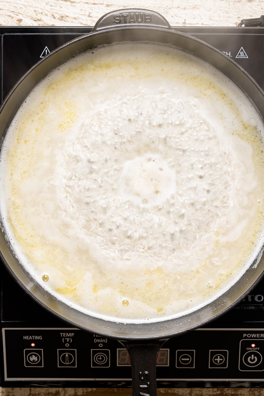 Basmati rice boiling in skillet with water.