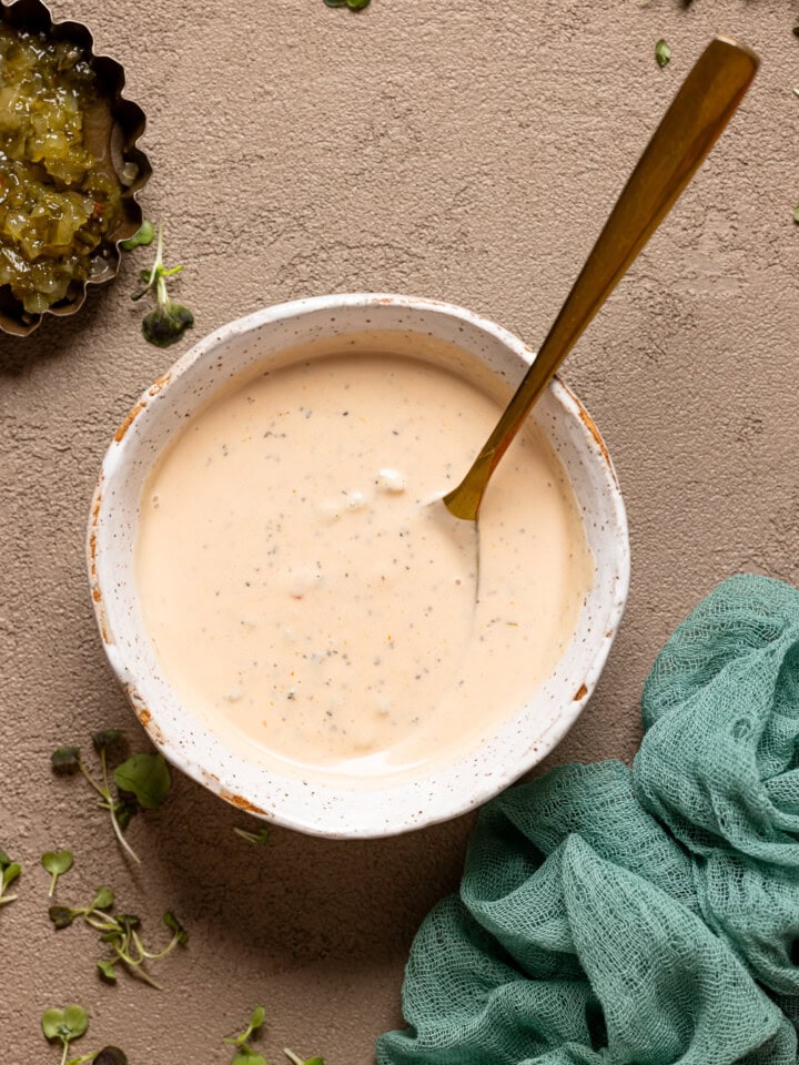 Sauce in a white bowl with a gold spoon and a side of radish.