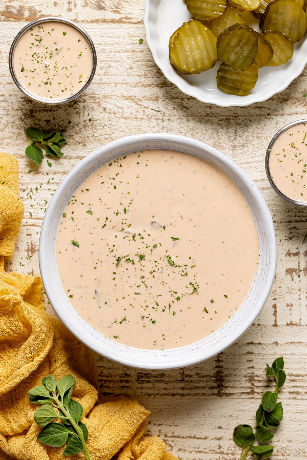 Sauce in a white bowl with sides of dipping sauces and pickles.