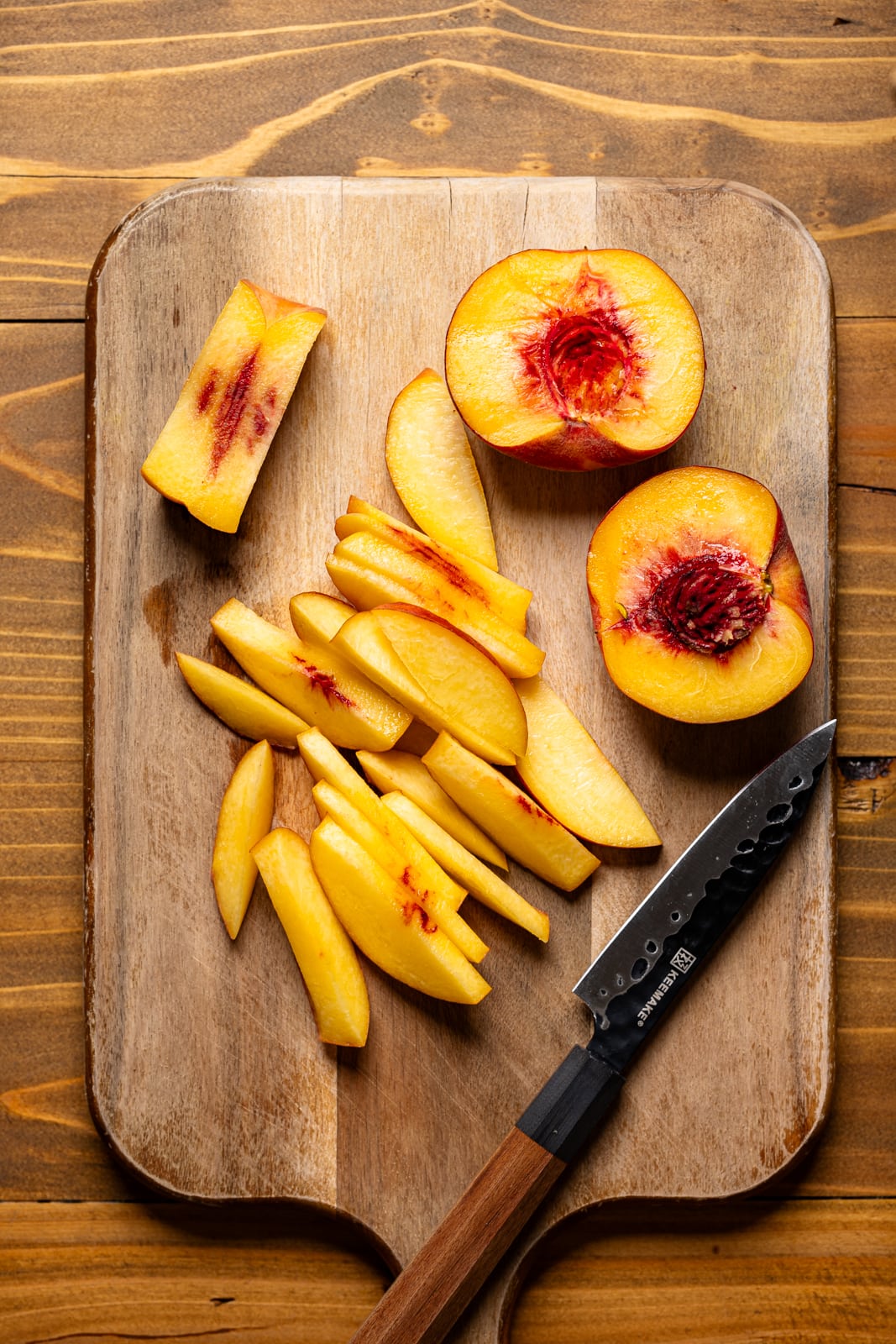 Sliced fresh peaches on a cutting board with a knife. 