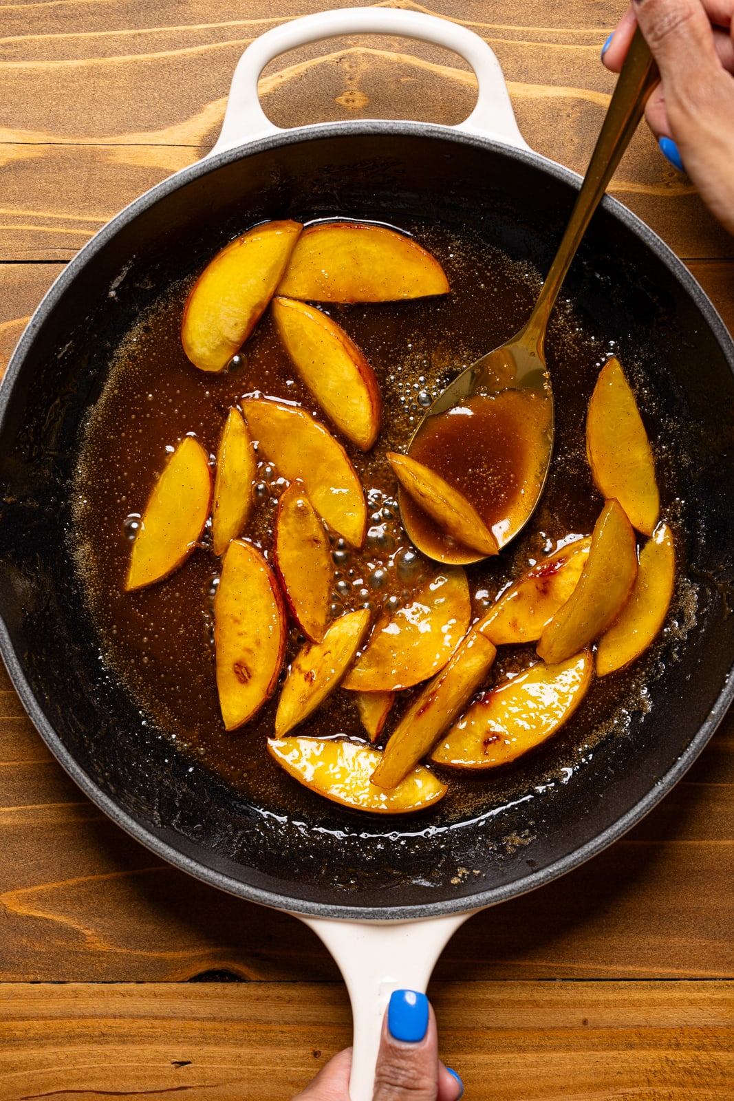 Sauteed peaches in a skillet with a golden spoon.