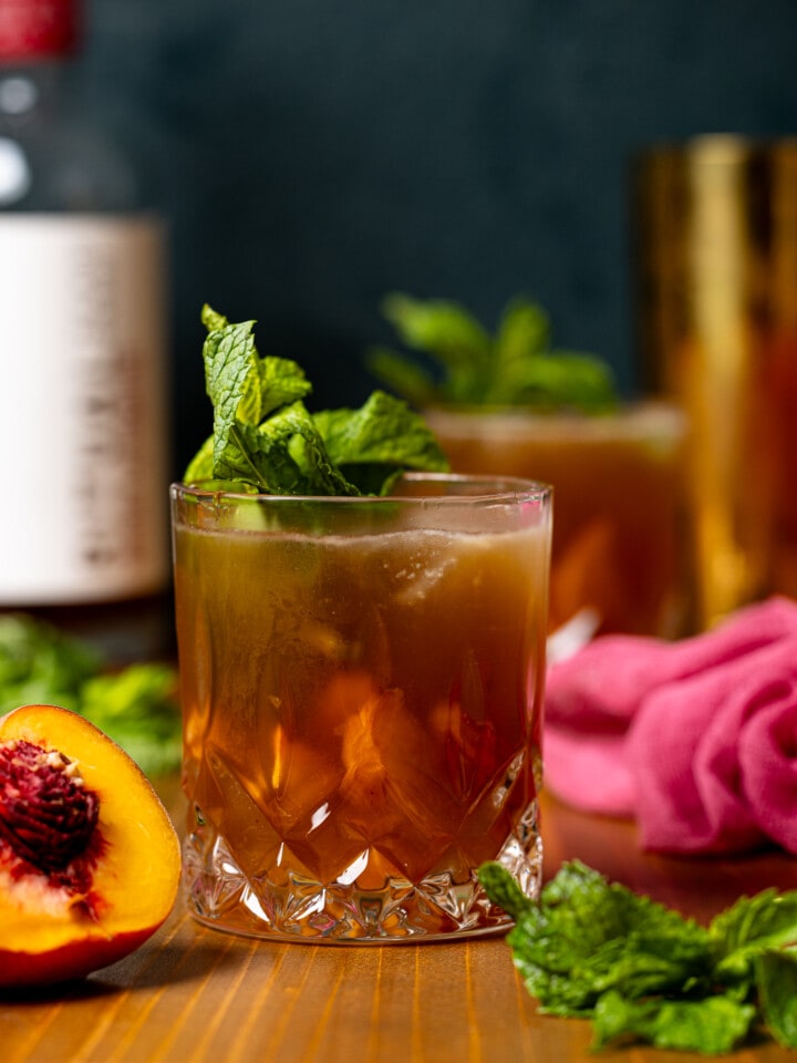 Mocktail in two glasses with peaches and mint leaves.