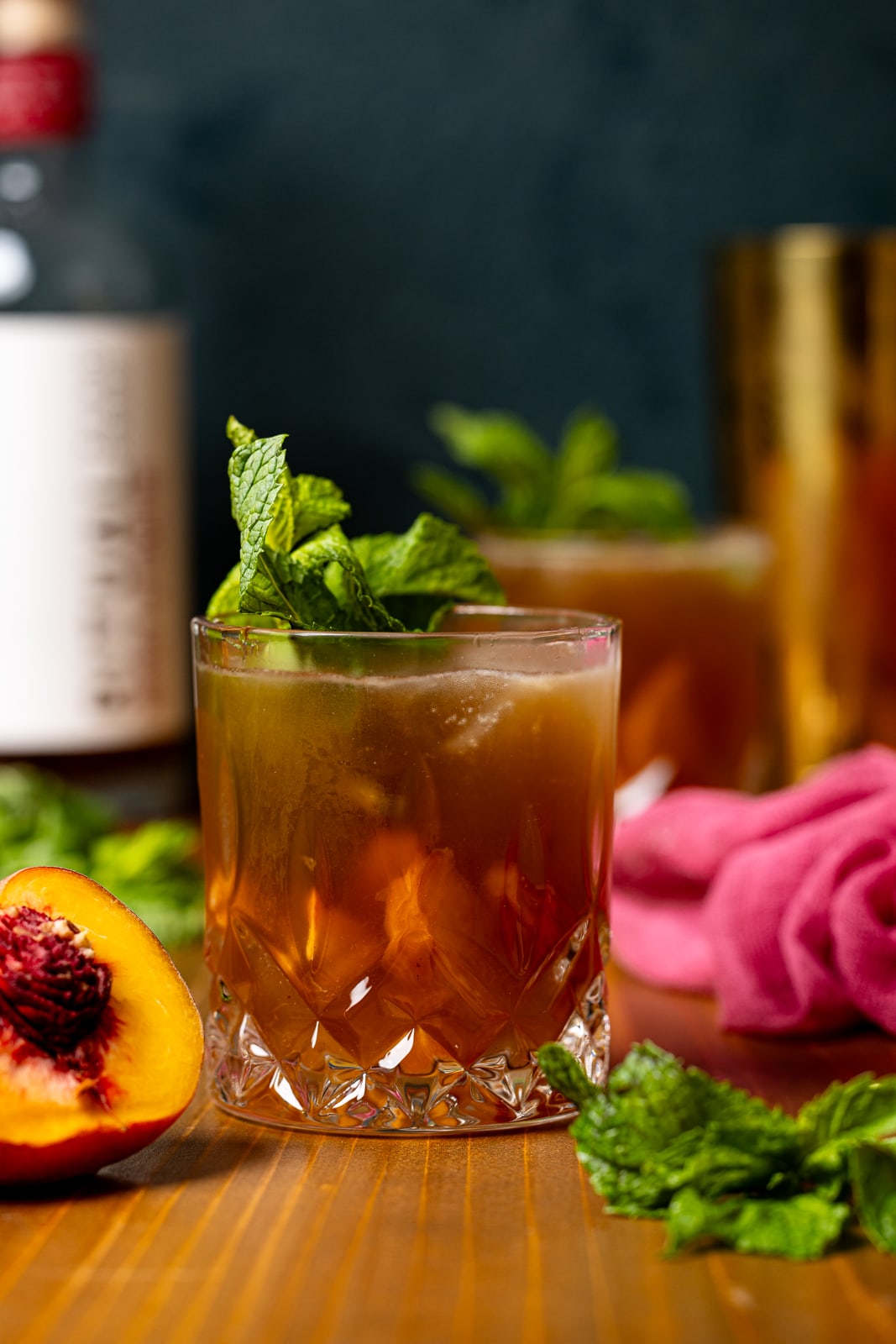 Mocktail in two glasses with peaches and mint leaves.