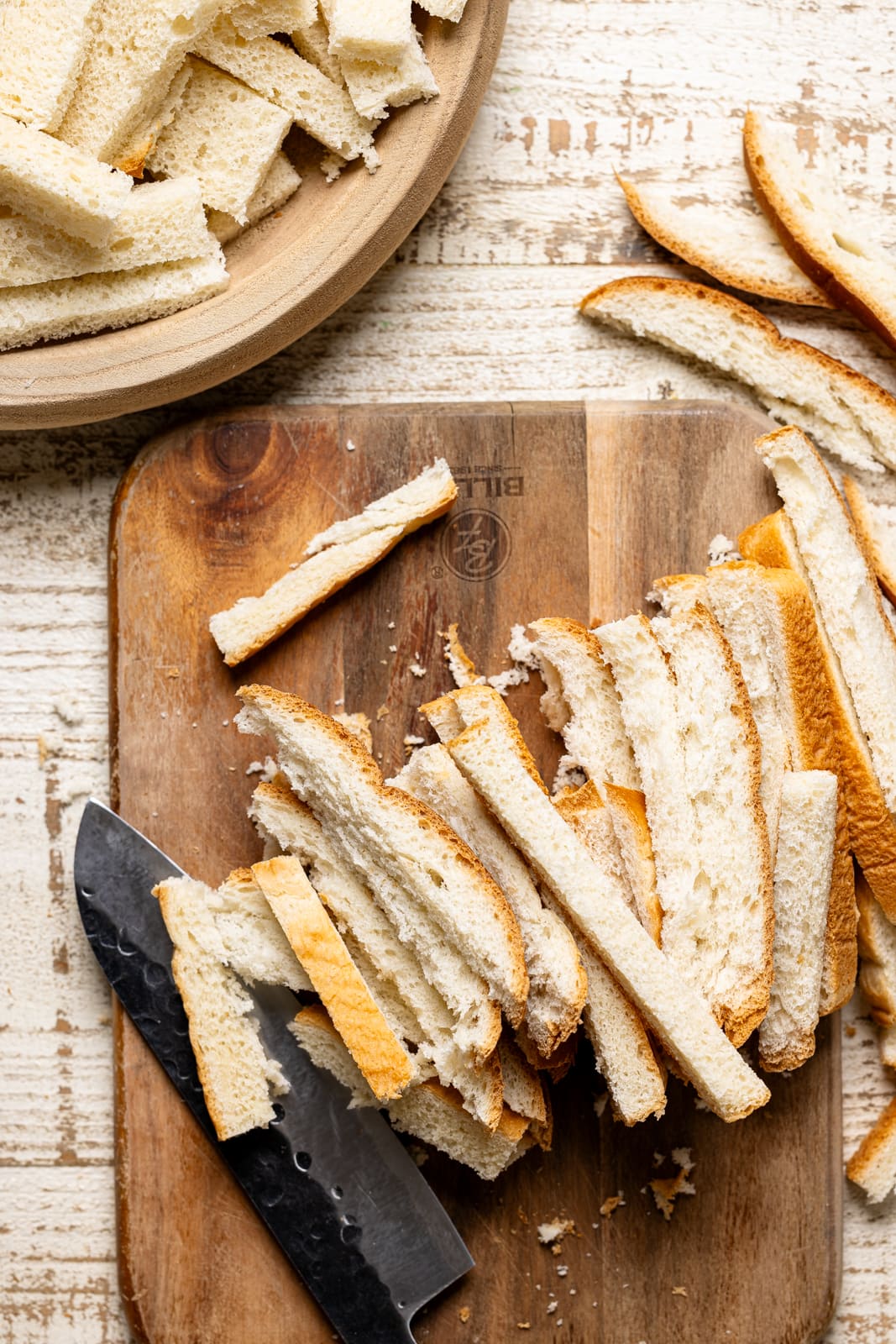 Bread ends cut unto a cutting board with a knife. 