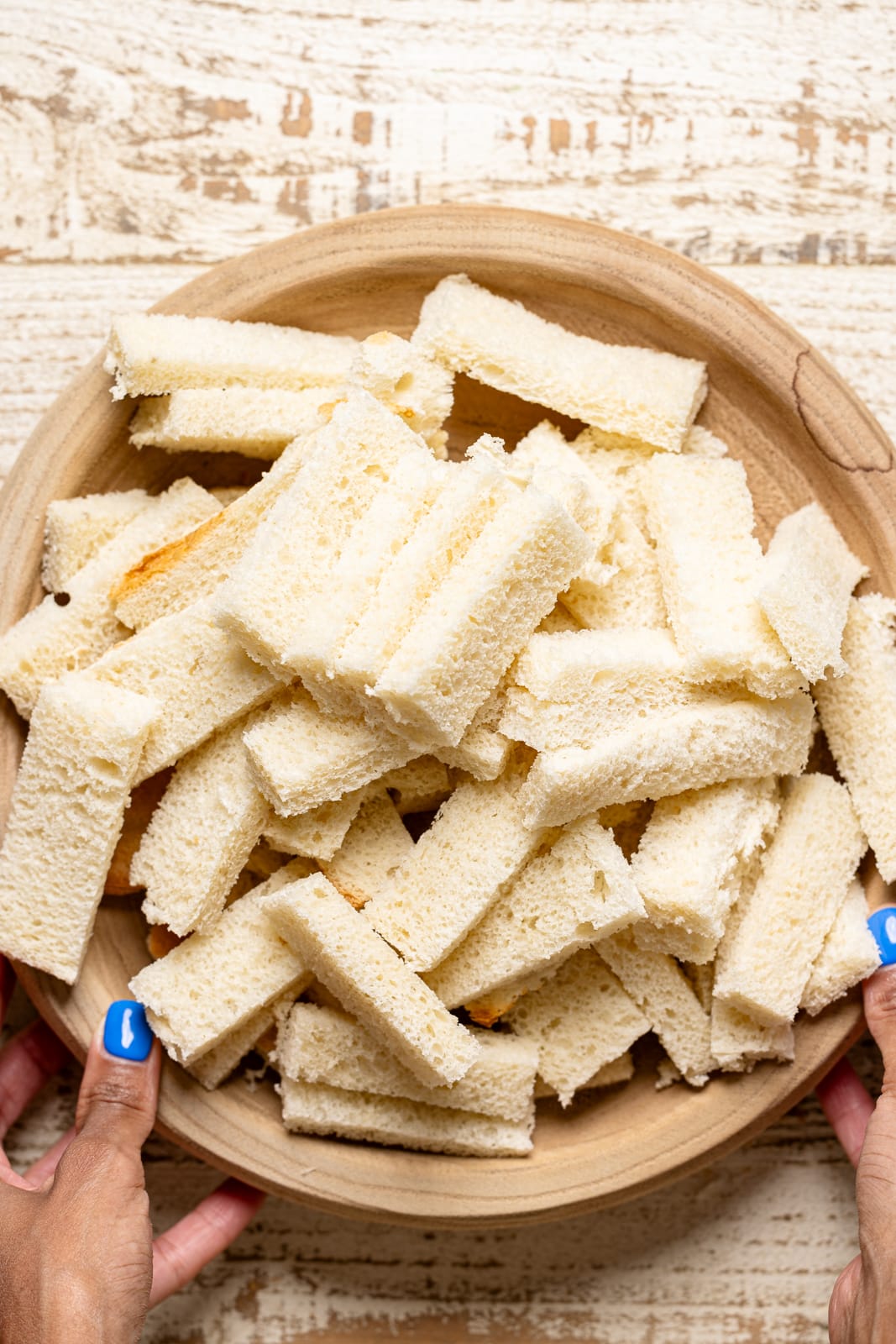 Cut slices of white bread in a bowl. 