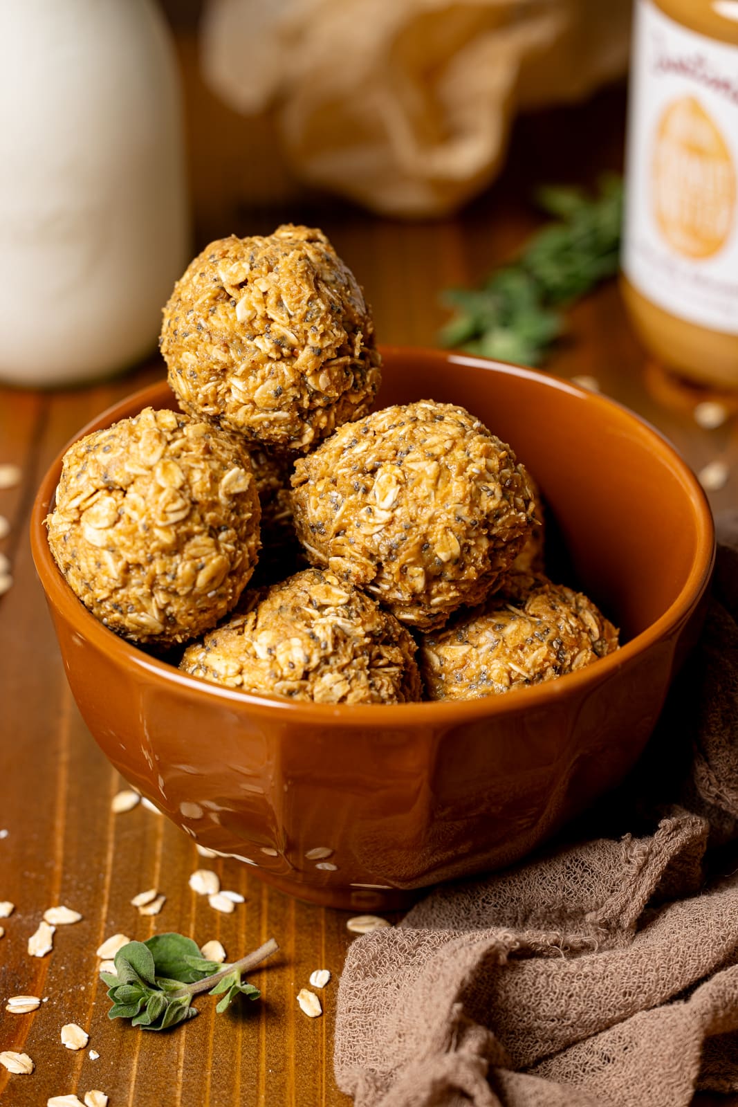 Energy balls in a brown bowl with milk and peanut butter in the background.