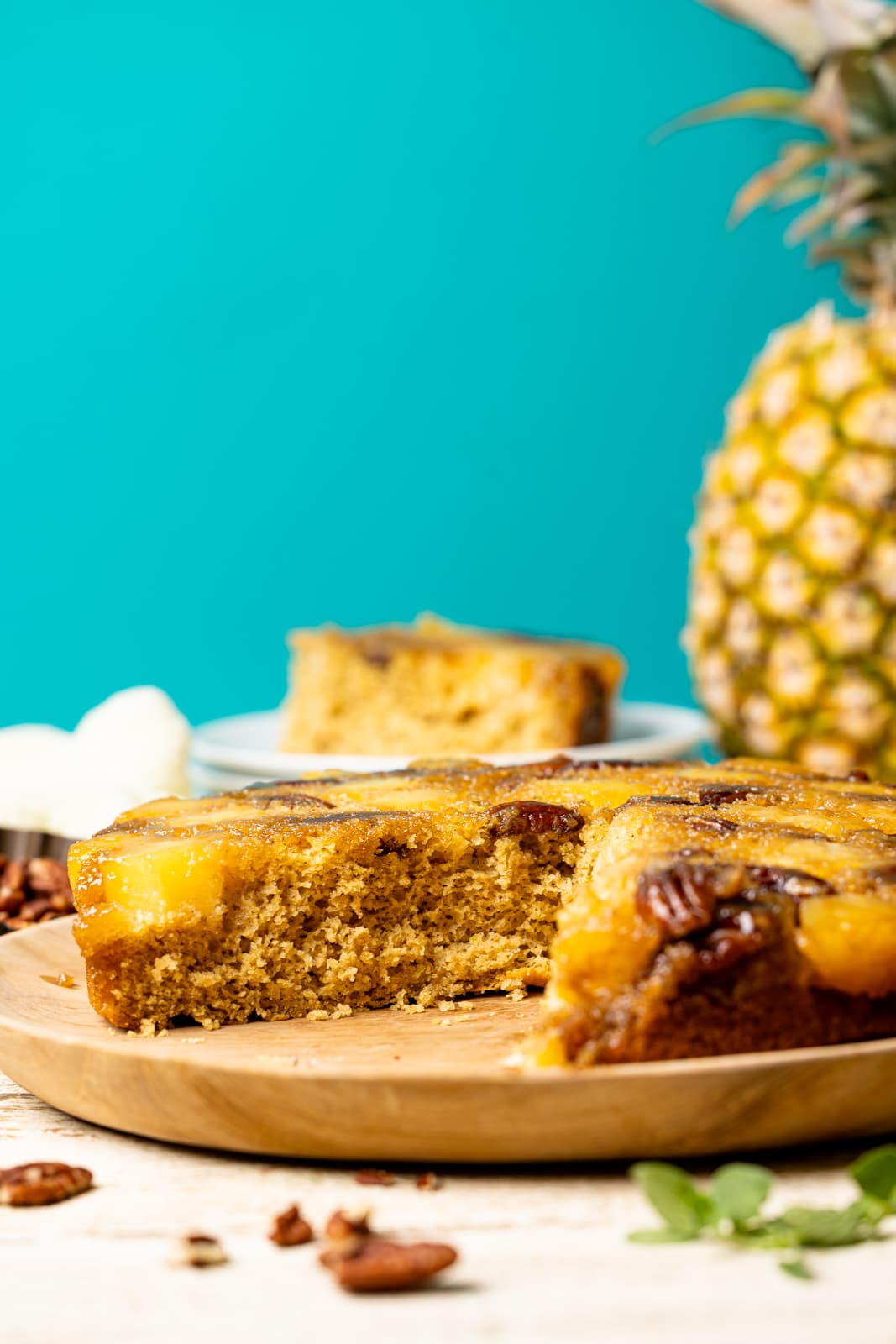 Cake with a slice with a pineapple in the background and pecans as garnish. A delicious fruity dessert
