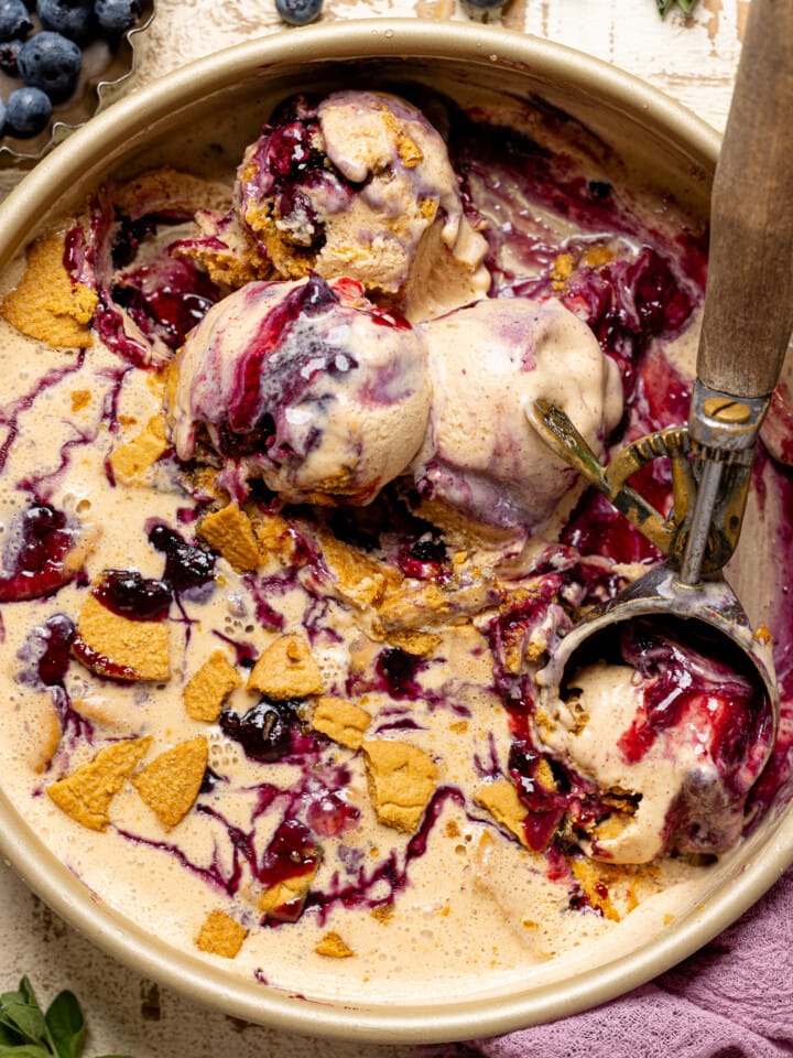 Up close of scoops of ice cream in round pan with blueberries.
