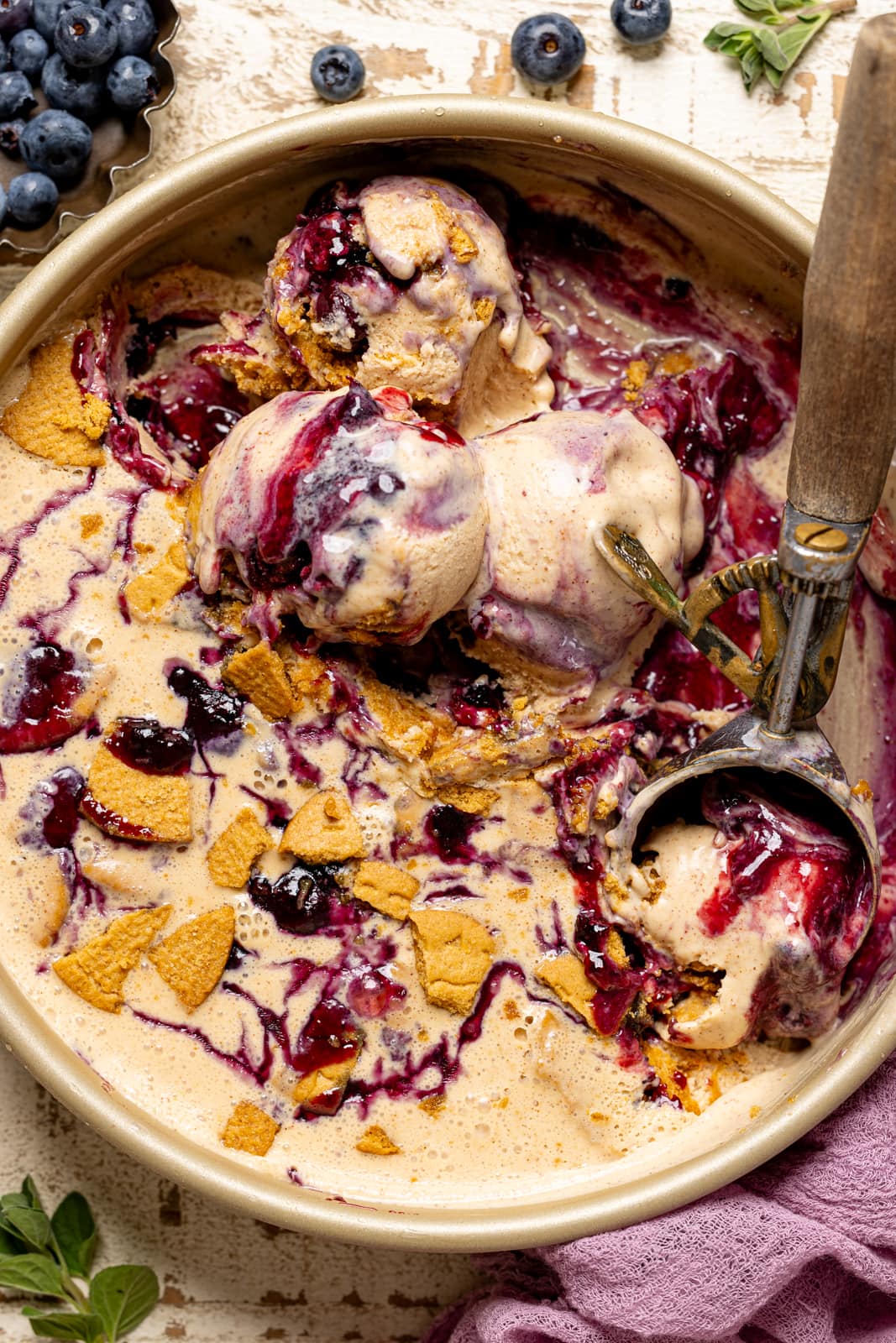 Up close of scoops of ice cream in round pan with blueberries.