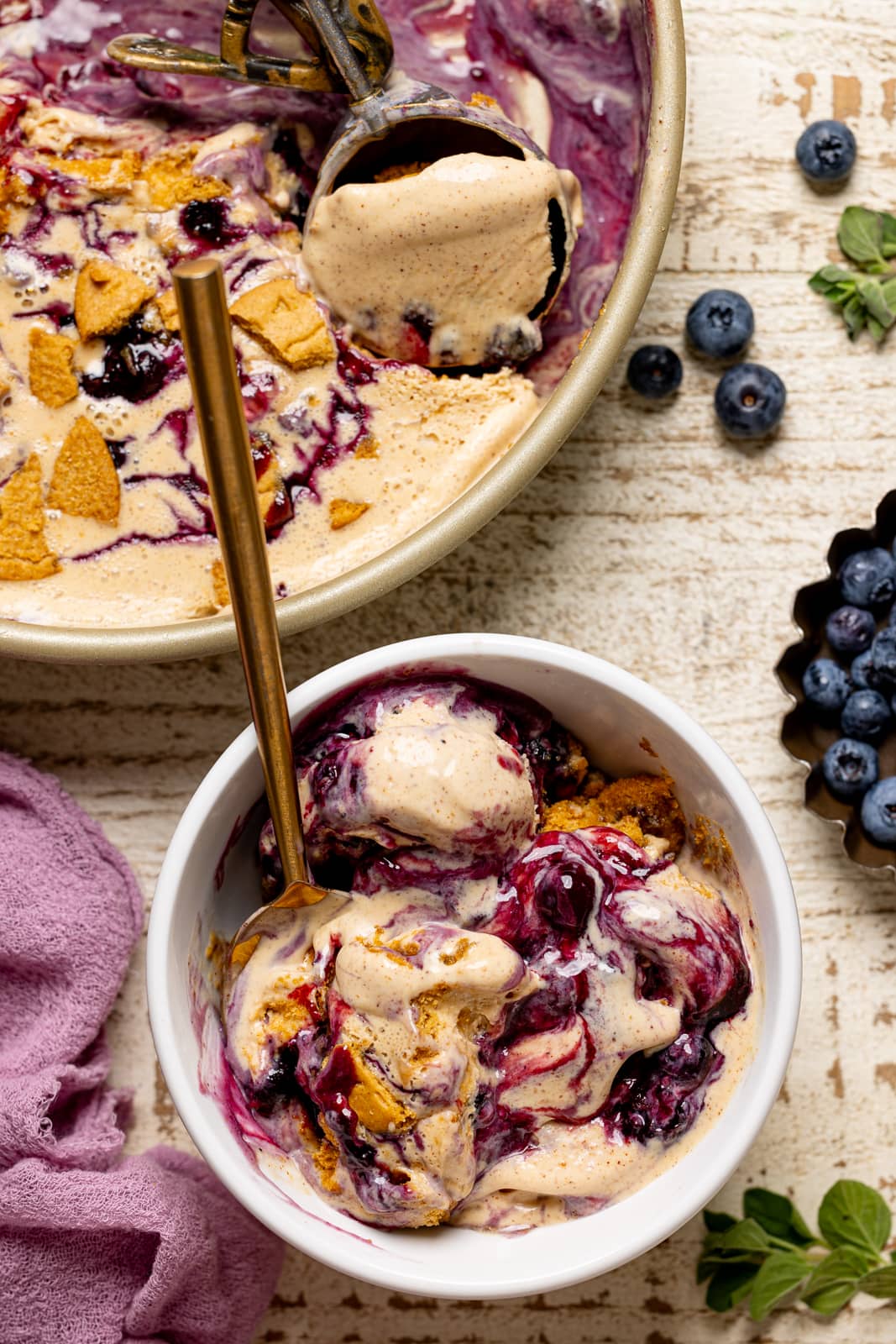 Ice cream in a bowl with spoon and blueberries.