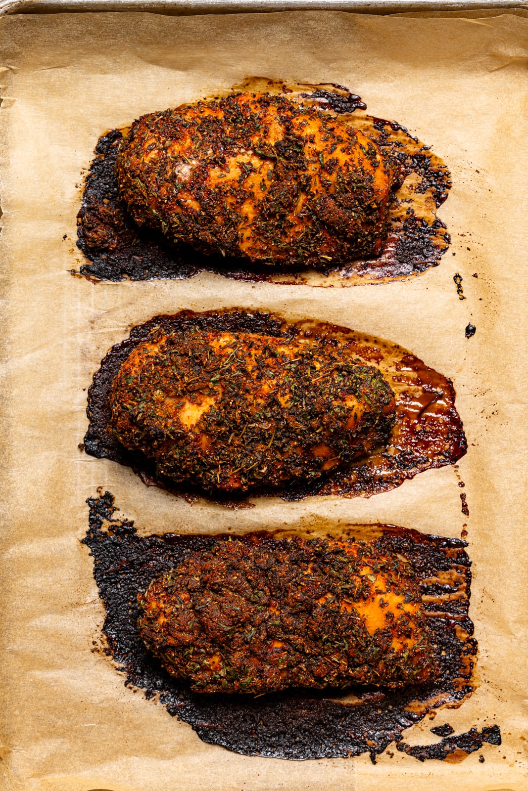 Baked chicken on a baking sheet with parchment paper.