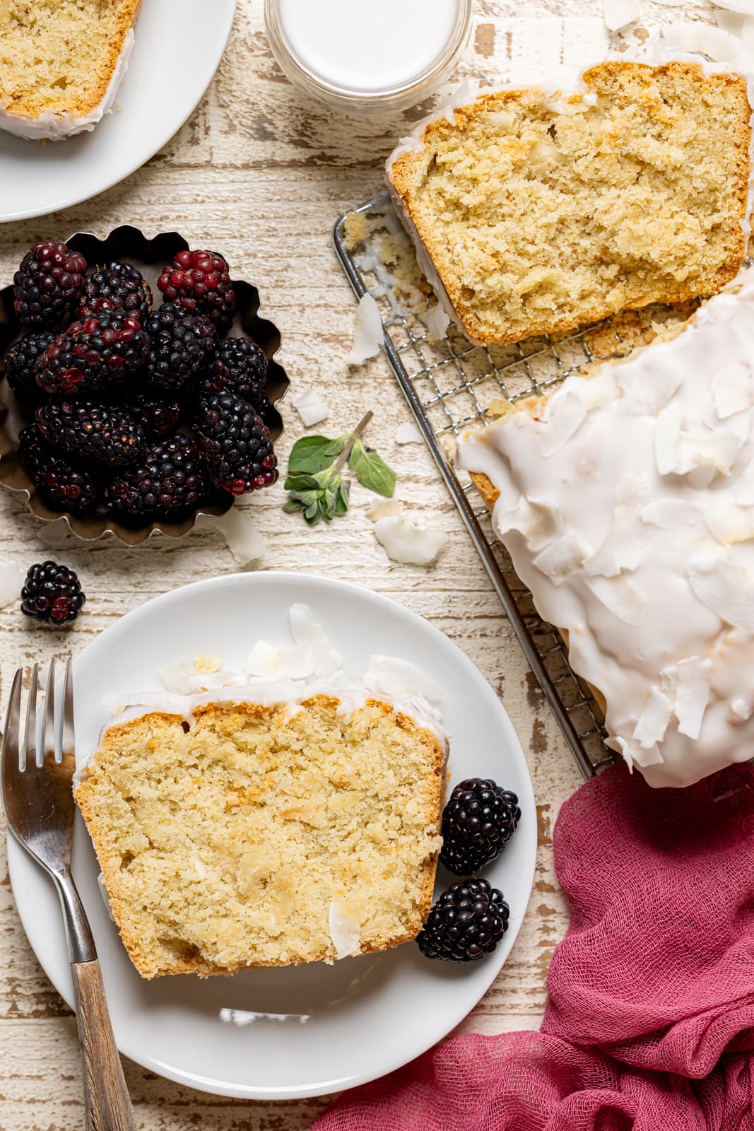 Sliced bread on a white plate with a fork and blackberries.