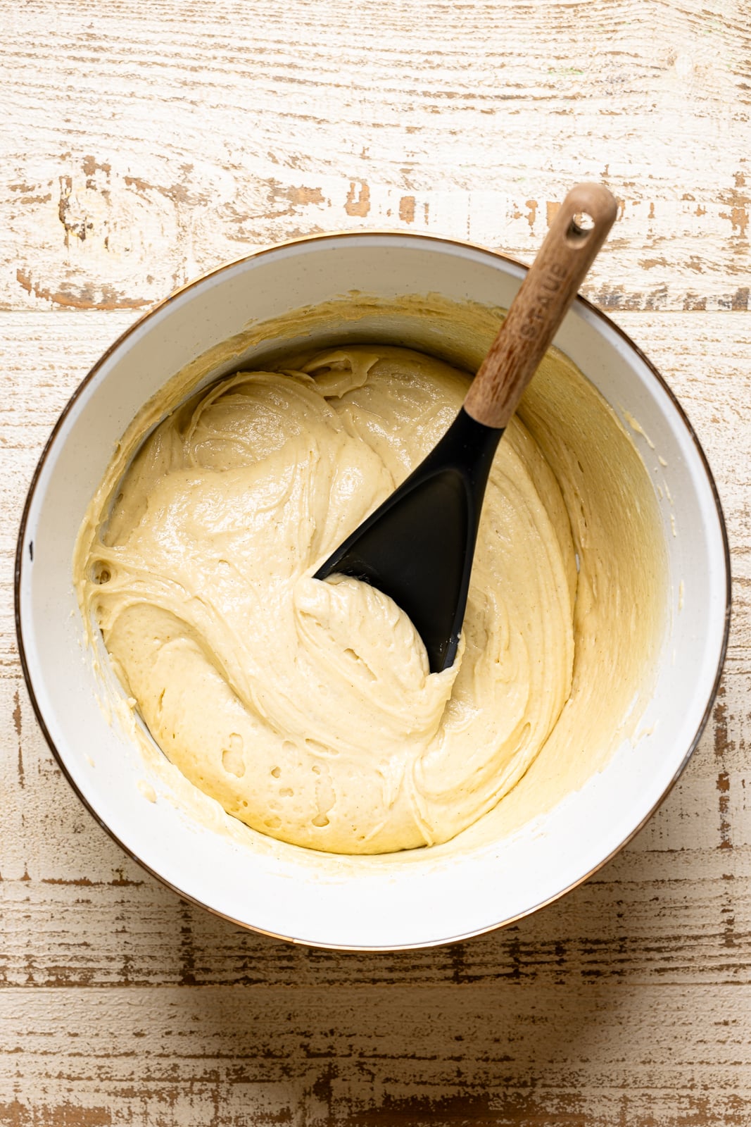 Bread batter in a white bowl with a spoon.