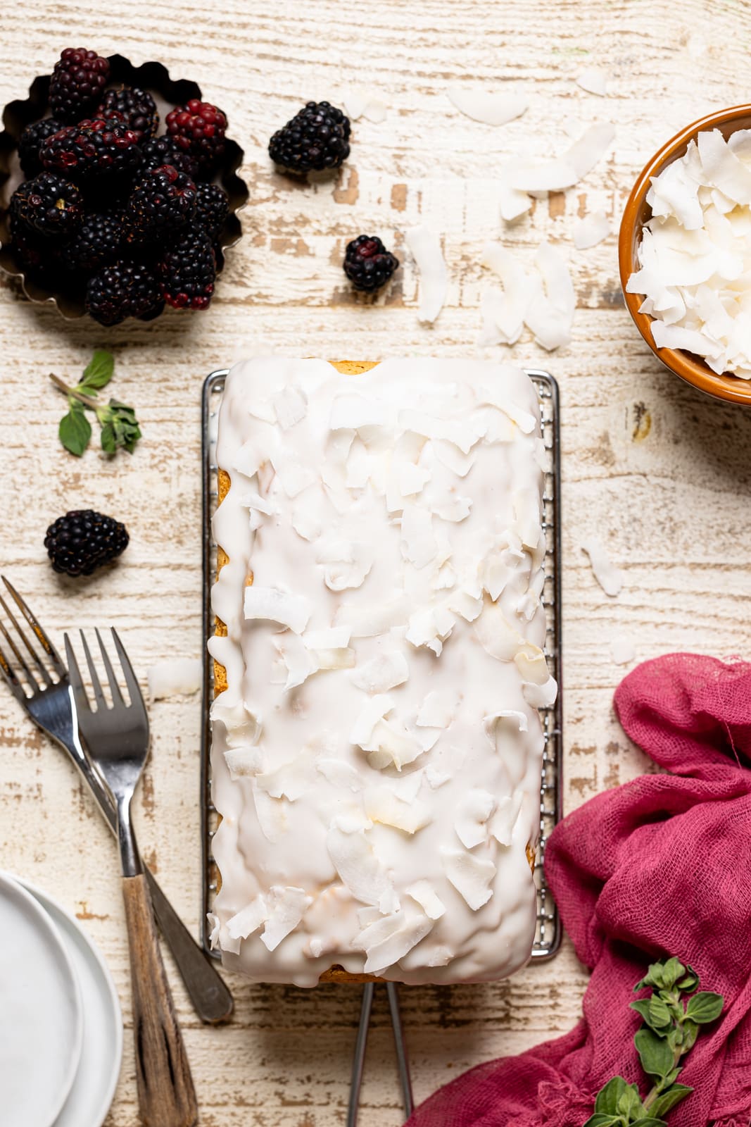 Bread with coconut flakes, two forks, and blackberries. 